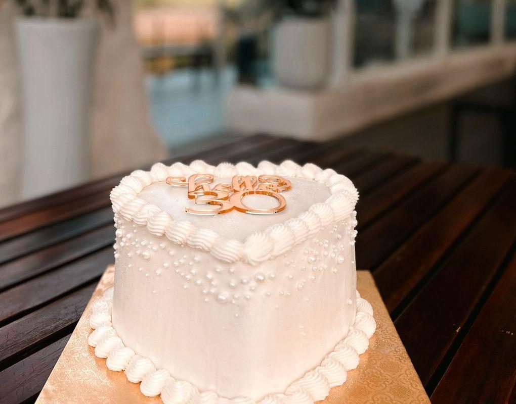 Gâteau cœur blanc perlé avec cache-nom doré, en terrasse
